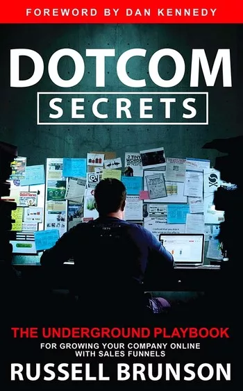 Cover of the book "Dotcom Secrets: The Underground Playbook" by Russell Brunson, featuring a person working at a cluttered desk with multiple papers on the wall, and a foreword by Dan Kennedy.