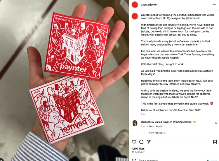 Two hands holding red and white sew-on patches from Paynterjacket's Limited Edition Batch №7. The patches feature illustrations and text, with one referencing a New York Times feature.