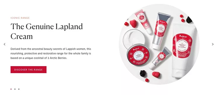 A display of skincare products from "The Genuine Lapland Cream" range, including creams and tubes surrounded by raspberries, blueberries, and blackberries. Text highlights the product’s restorative attributes.