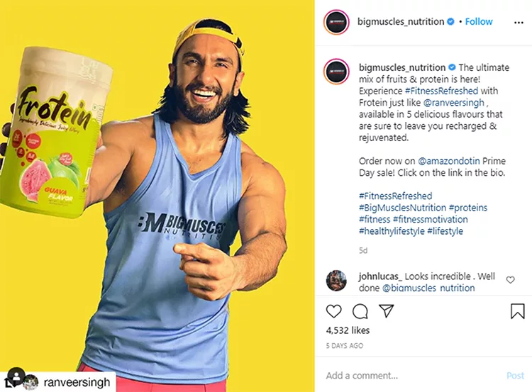 A person in a blue athletic tank top, holding a container of protein powder and smiling against a yellow background. Instagram text promotes the product and mentions "bigmuscles_nutrition".