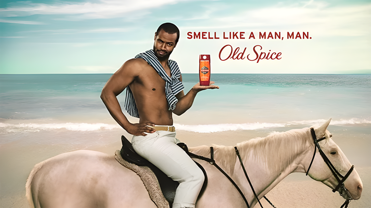 A shirtless man on a horse at the beach holds up a bottle of Old Spice body wash. Text reads, "Smell like a man, man. Old Spice.