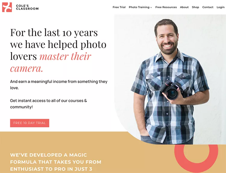 Man holding a camera stands in front of a promotional banner for photo training courses.